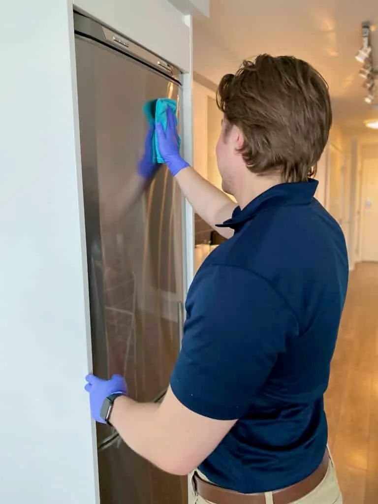 Whiskey Jack team member cleaning a stainless steel fridge